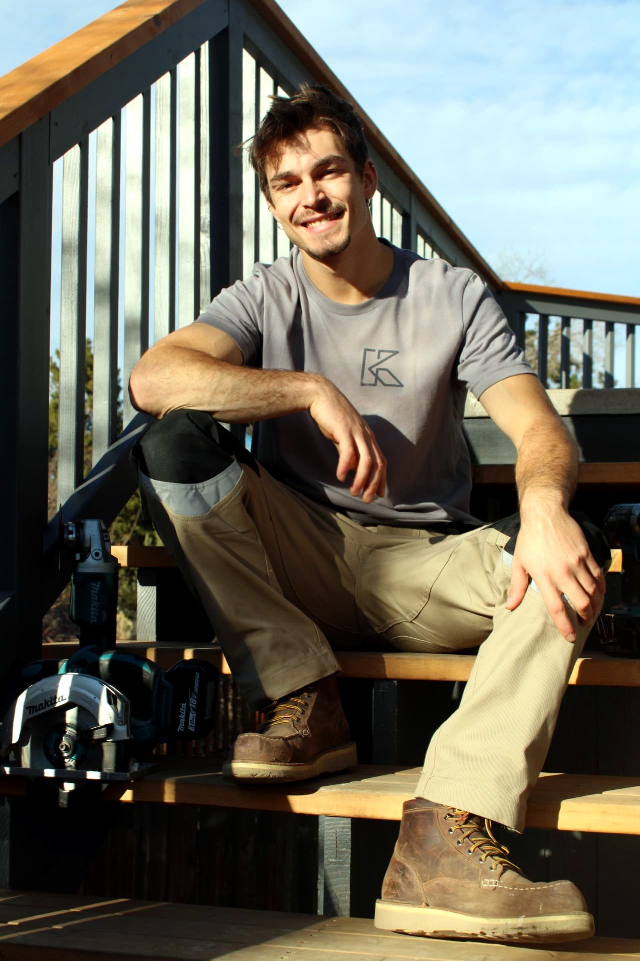 Kumara, owner of Kaybee LLC Construction, sitting on a cedar staircase with his tools