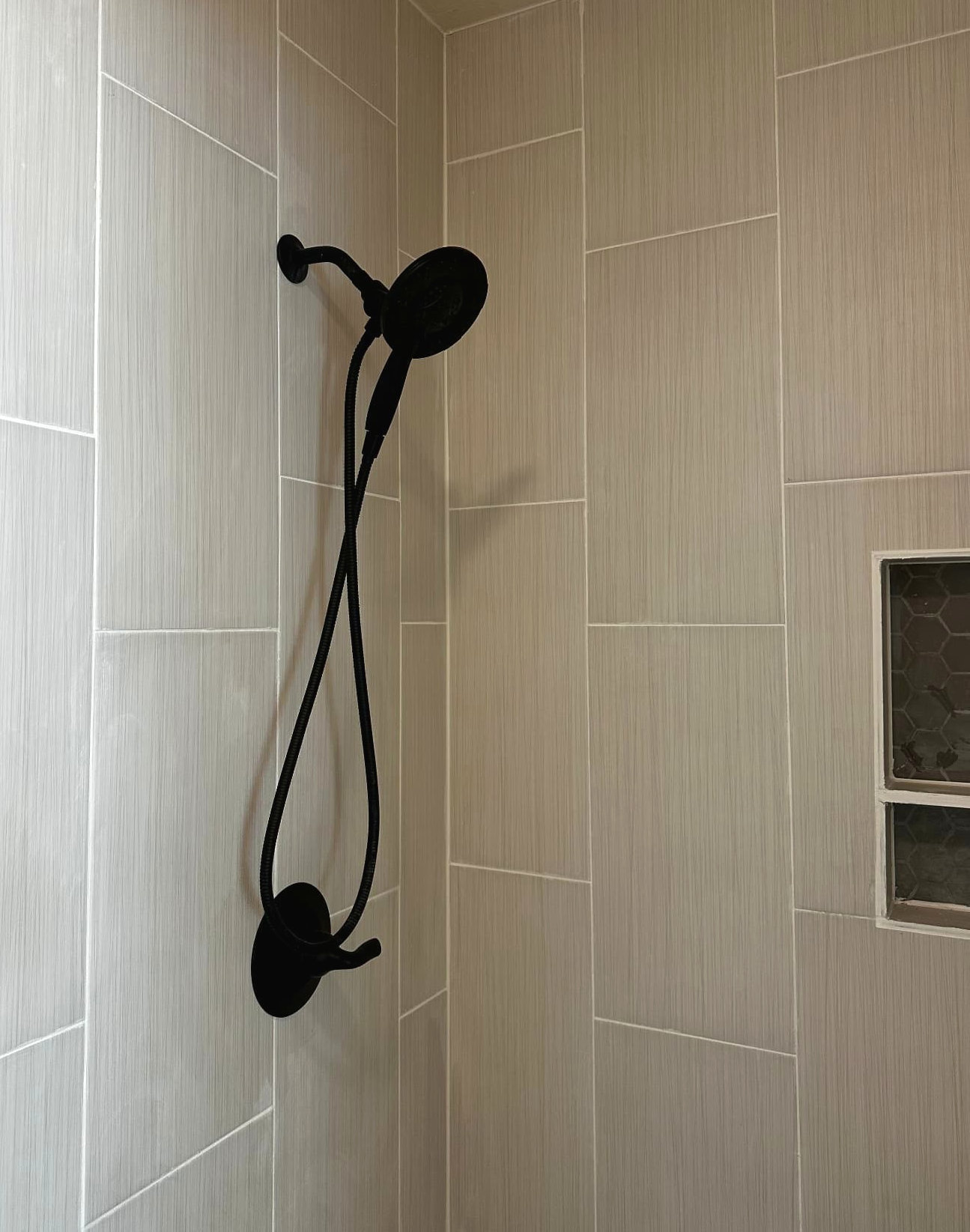Shower with vertical textured tile and matte black shower head and controls