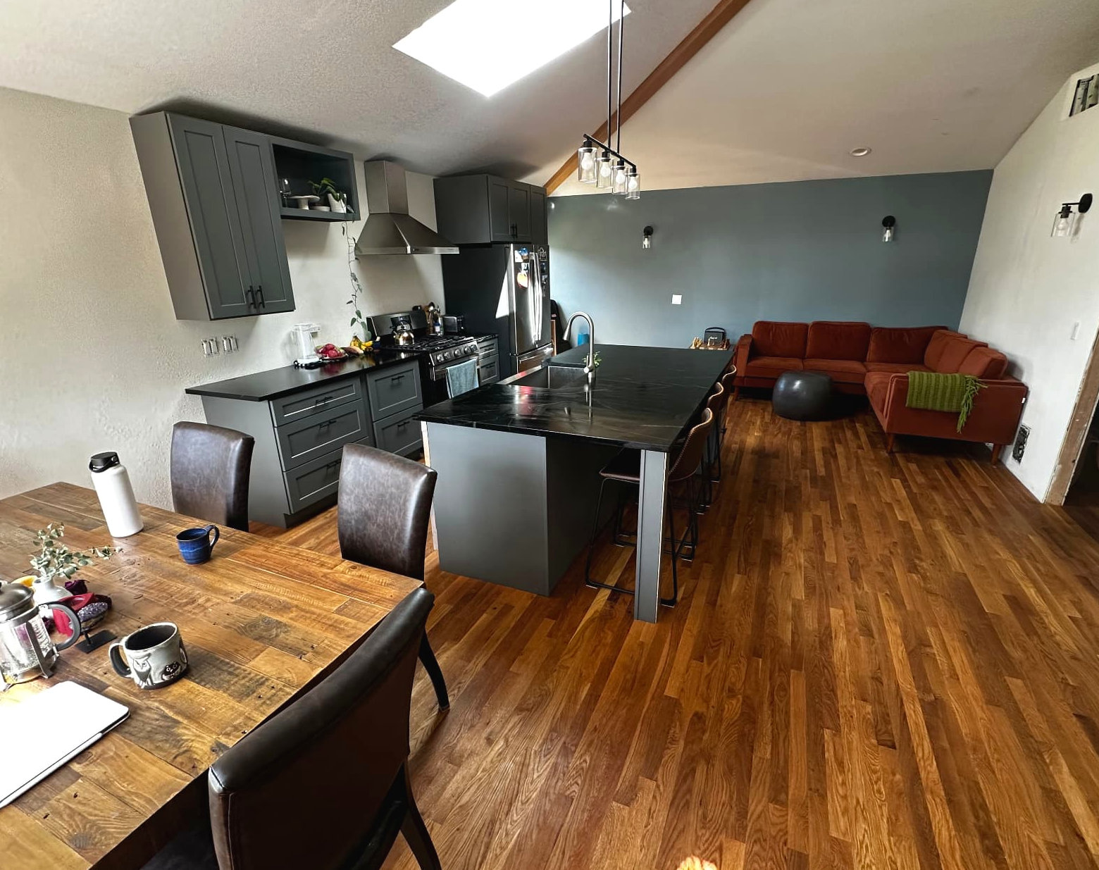 Wide view across a kitchen and living room with a dark island and wood floors