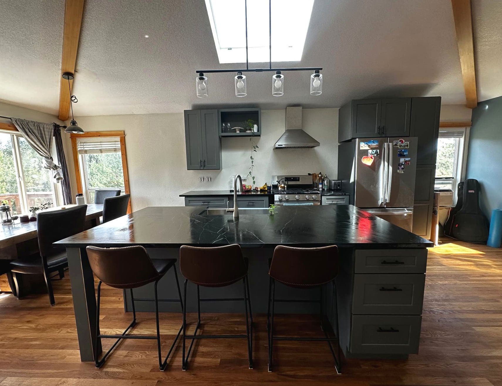 Open kitchen with dark cabinets, a large black island, and a skylight above