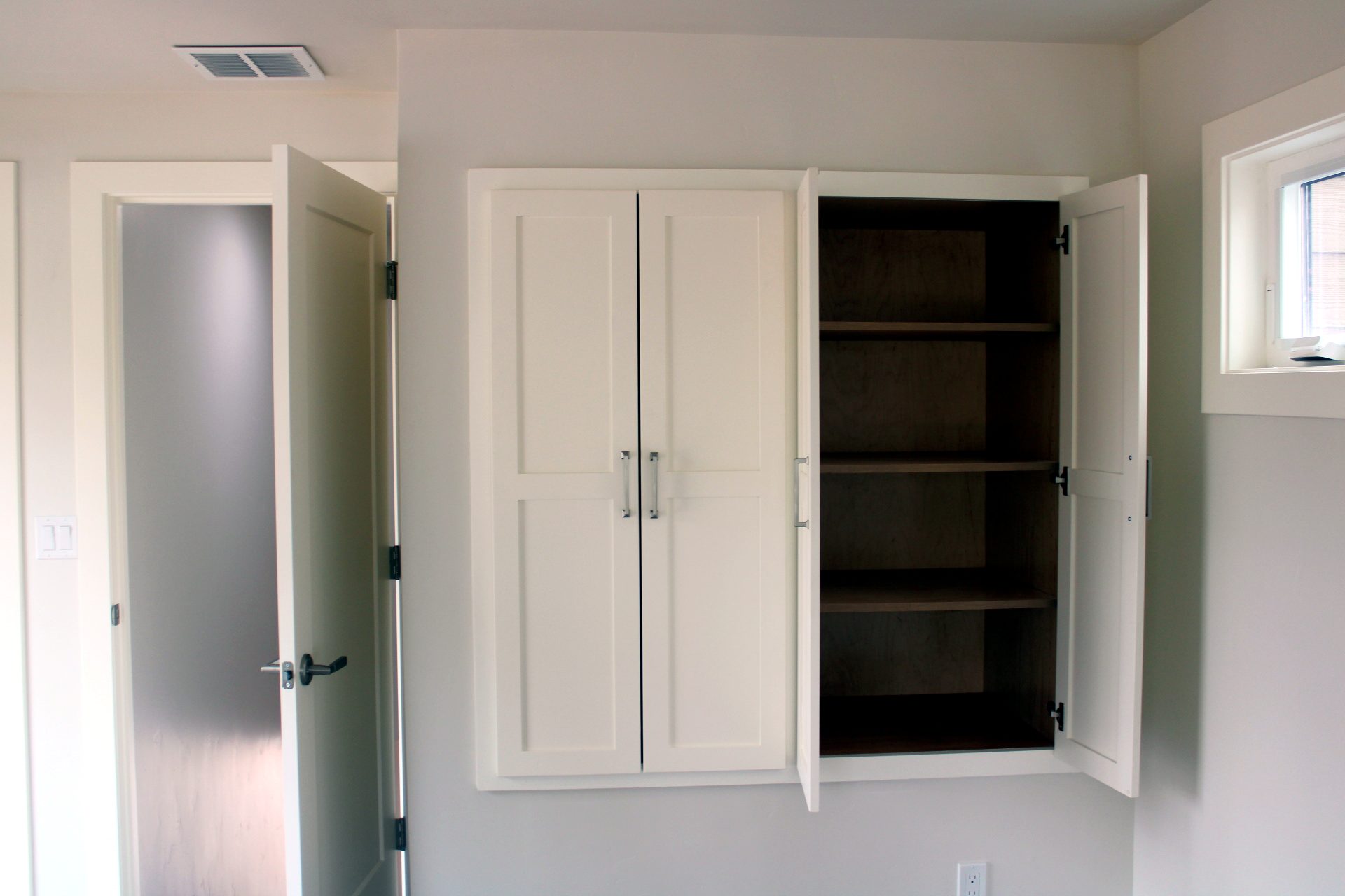 White built-in cabinets with one door open to show the shelves