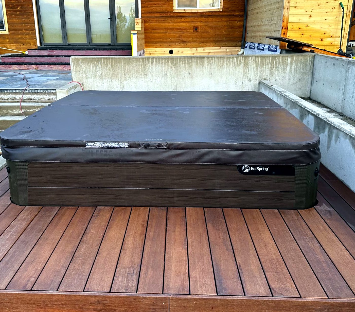 Hot tub set into hardwood deck boards with concrete walls alongside
